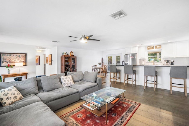 living area with wood-type flooring, visible vents, and a ceiling fan