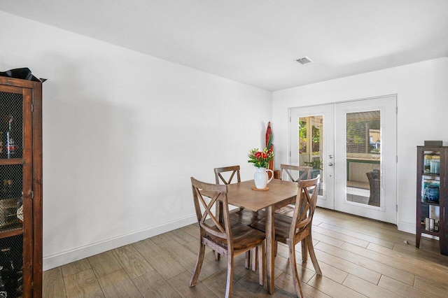 dining room featuring french doors, visible vents, baseboards, and wood finished floors