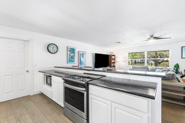 kitchen with white cabinets, dark countertops, open floor plan, stainless steel electric range, and wood finish floors