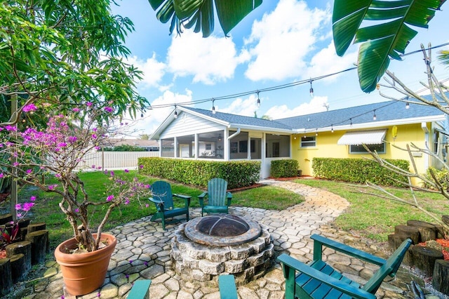 back of property featuring a fire pit, a sunroom, fence, a patio area, and stucco siding