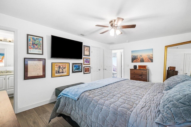 bedroom featuring visible vents, connected bathroom, a sink, wood finished floors, and baseboards