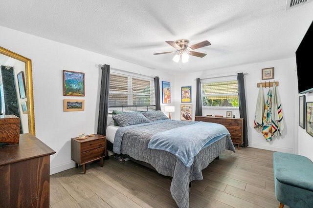 bedroom featuring visible vents, multiple windows, light wood-style flooring, and a textured ceiling