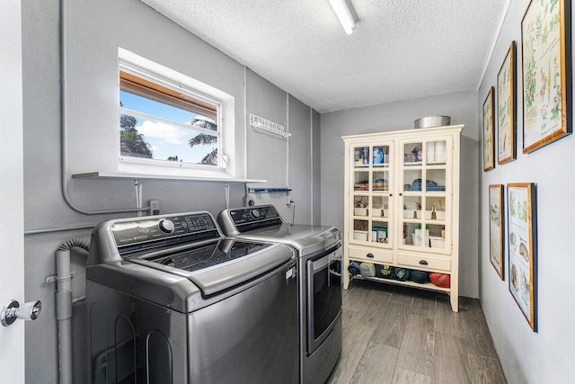 washroom featuring laundry area, a textured ceiling, separate washer and dryer, and wood finished floors