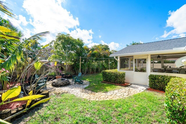 view of yard featuring a sunroom, a fenced backyard, a patio area, and a fire pit