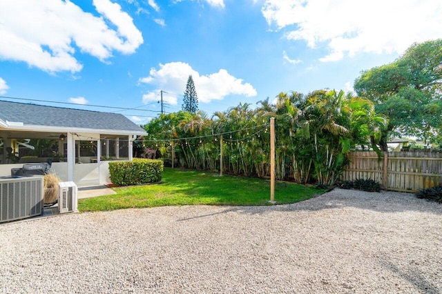 view of yard featuring central air condition unit, a patio area, fence, and a sunroom