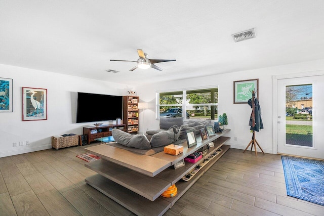 living room featuring baseboards, wood finished floors, visible vents, and a ceiling fan