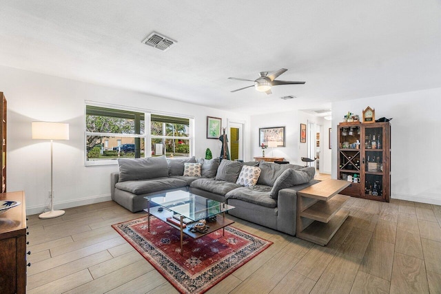 living area featuring ceiling fan, wood finished floors, visible vents, and baseboards