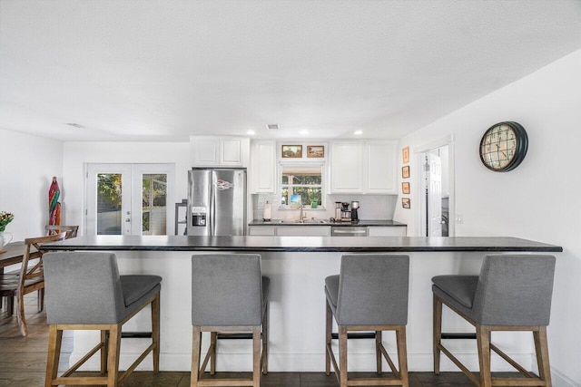 kitchen featuring stainless steel appliances, french doors, white cabinetry, and a kitchen breakfast bar