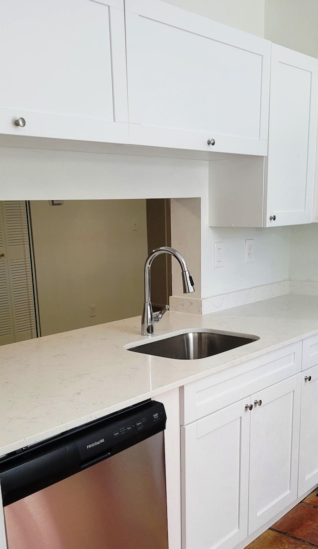 kitchen with light stone counters, dishwasher, white cabinets, and sink