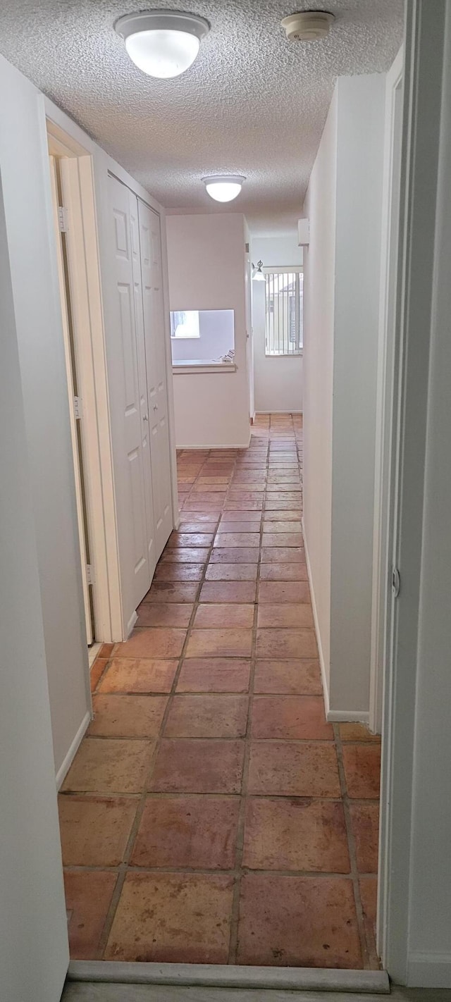 corridor featuring light tile patterned floors and a textured ceiling