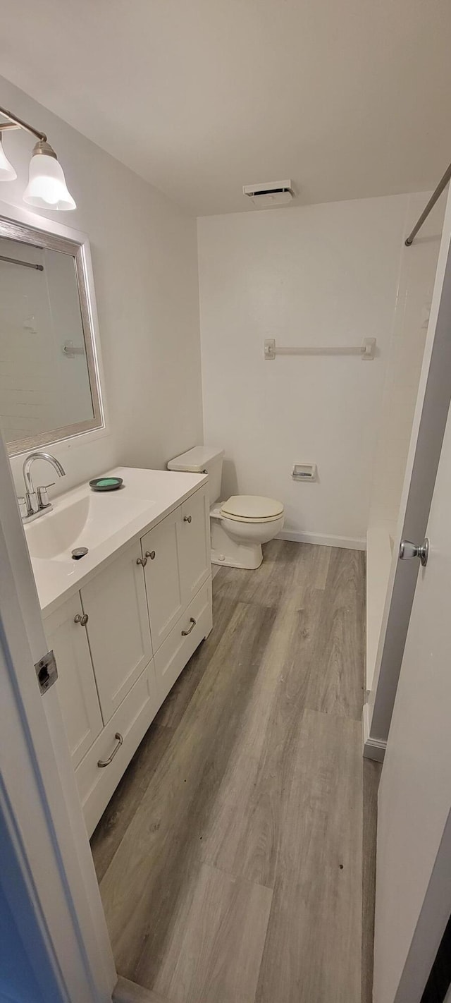 bathroom with vanity, hardwood / wood-style flooring, toilet, and walk in shower