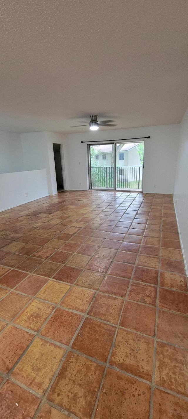 empty room with ceiling fan and a textured ceiling