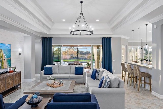 living room featuring crown molding, a raised ceiling, and a notable chandelier