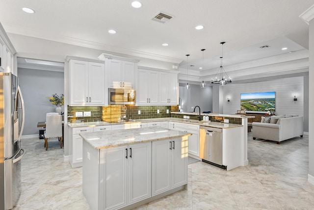 kitchen with stainless steel appliances, a kitchen island, pendant lighting, white cabinets, and sink