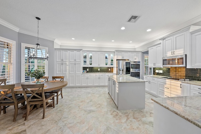 kitchen featuring white cabinets, hanging light fixtures, appliances with stainless steel finishes, and tasteful backsplash