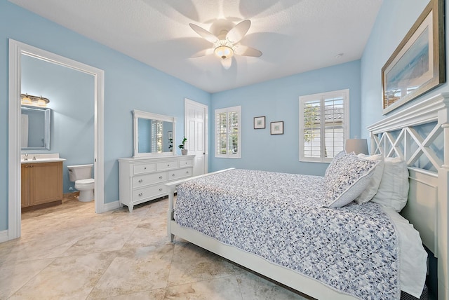 bedroom with ceiling fan, sink, ensuite bathroom, and a textured ceiling