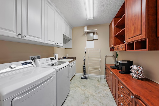 washroom with cabinets, a textured ceiling, separate washer and dryer, and sink