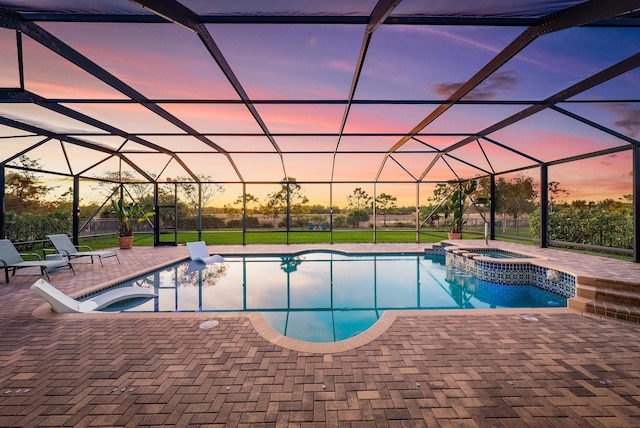 pool at dusk with a lanai and an in ground hot tub