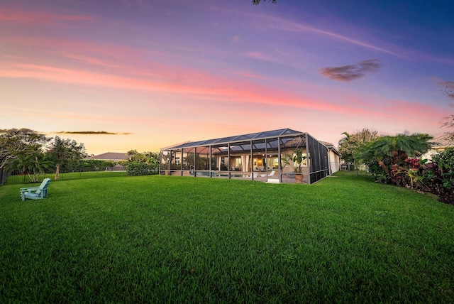 yard at dusk featuring glass enclosure and a pool