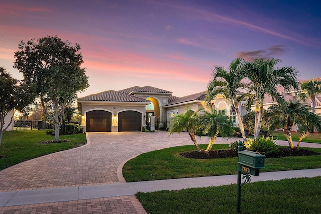 mediterranean / spanish-style house with a garage and a yard