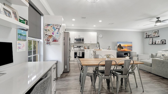 dining space with hardwood / wood-style floors, ceiling fan, sink, and crown molding