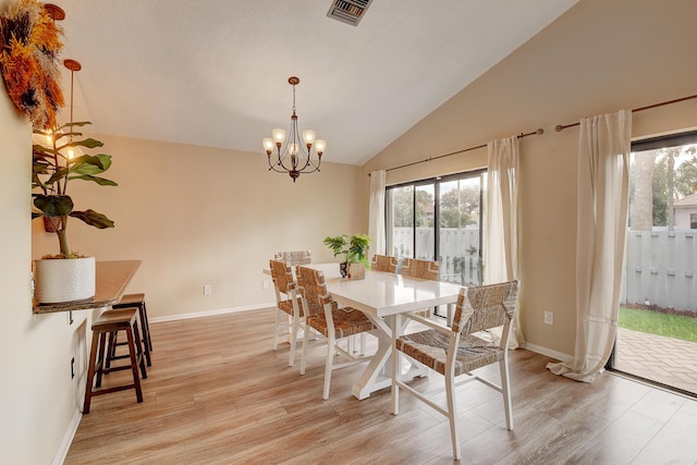 dining space with lofted ceiling, light wood-type flooring, and a notable chandelier