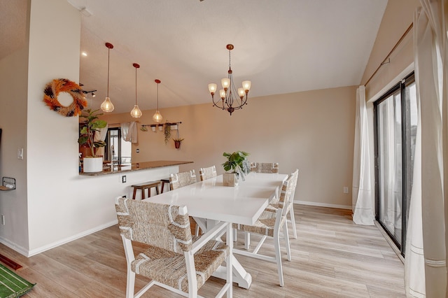 dining space featuring light hardwood / wood-style floors, lofted ceiling, and an inviting chandelier