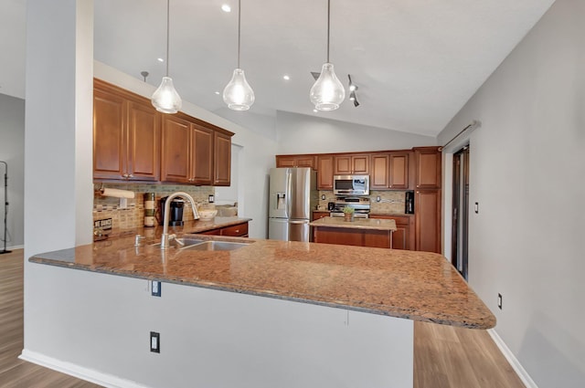 kitchen with decorative light fixtures, sink, kitchen peninsula, and stainless steel appliances