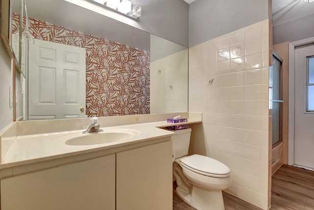 full bathroom with toilet, bath / shower combo with glass door, vanity, and hardwood / wood-style flooring