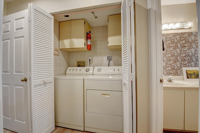 washroom with cabinets, washer and clothes dryer, and sink