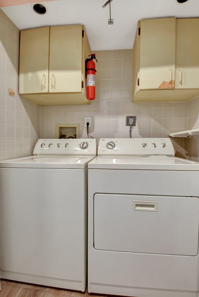 clothes washing area featuring washer and dryer, cabinets, and light wood-type flooring