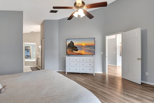 bedroom with ceiling fan, high vaulted ceiling, connected bathroom, and hardwood / wood-style flooring