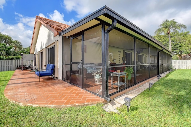 view of home's exterior with a sunroom, a lawn, and a patio