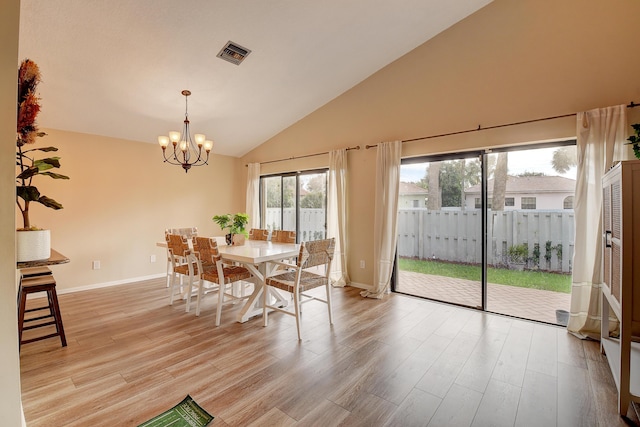 dining space with light wood-type flooring, vaulted ceiling, and a chandelier