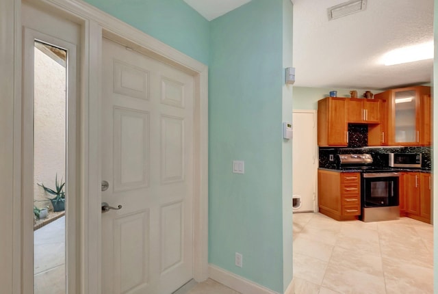 kitchen featuring a textured ceiling, stainless steel appliances, and backsplash