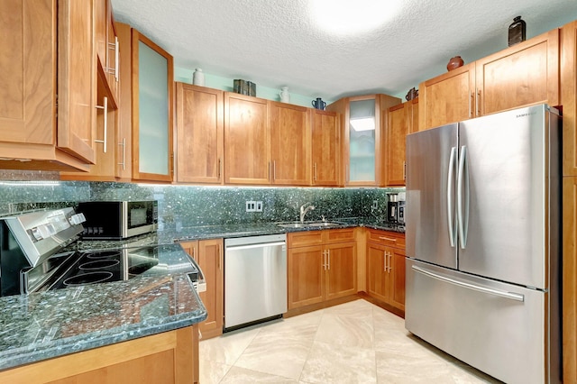 kitchen featuring sink, dark stone counters, a textured ceiling, light tile patterned flooring, and appliances with stainless steel finishes