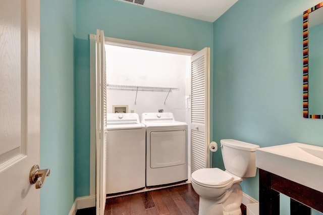 bathroom with hardwood / wood-style floors, toilet, and washing machine and clothes dryer