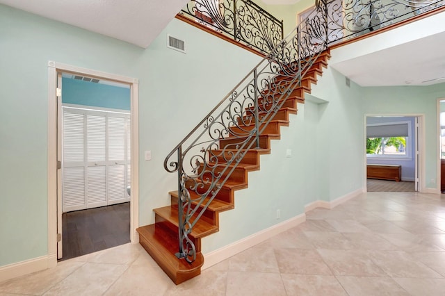 staircase with tile patterned flooring and a high ceiling