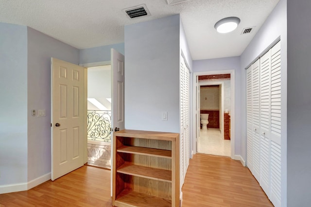 hallway featuring a textured ceiling and light hardwood / wood-style flooring