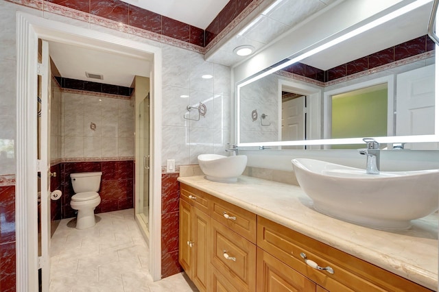 bathroom featuring tile patterned floors, walk in shower, vanity, tile walls, and toilet