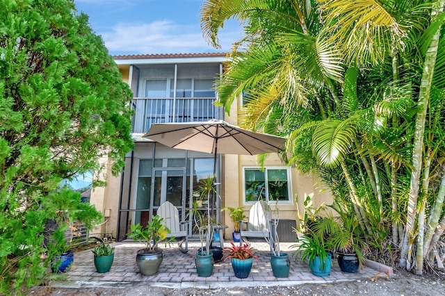 back of property with a sunroom, a balcony, and a patio