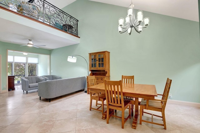 tiled dining space featuring a high ceiling and ceiling fan with notable chandelier