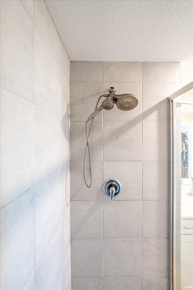 interior details with a tile shower and a textured ceiling