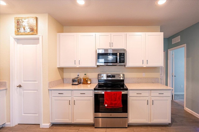 kitchen with white cabinets, light hardwood / wood-style floors, and stainless steel appliances