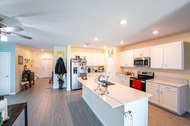 kitchen featuring white cabinetry, sink, stainless steel appliances, and a center island with sink