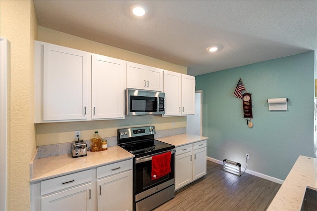 kitchen with white cabinets, appliances with stainless steel finishes, and dark hardwood / wood-style floors