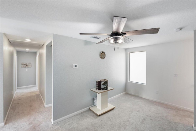 corridor with a textured ceiling and light carpet