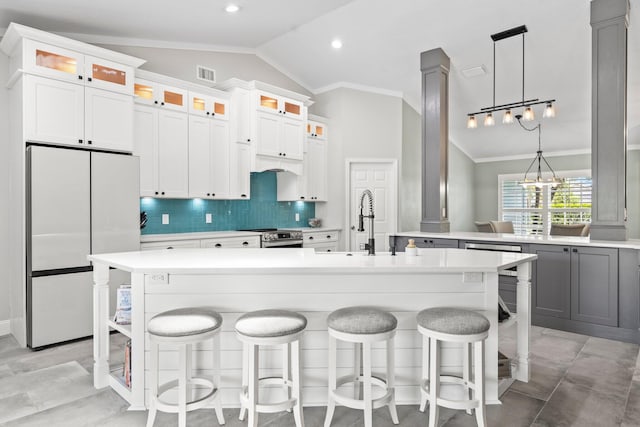 kitchen with white cabinets, white fridge, a kitchen island with sink, and vaulted ceiling