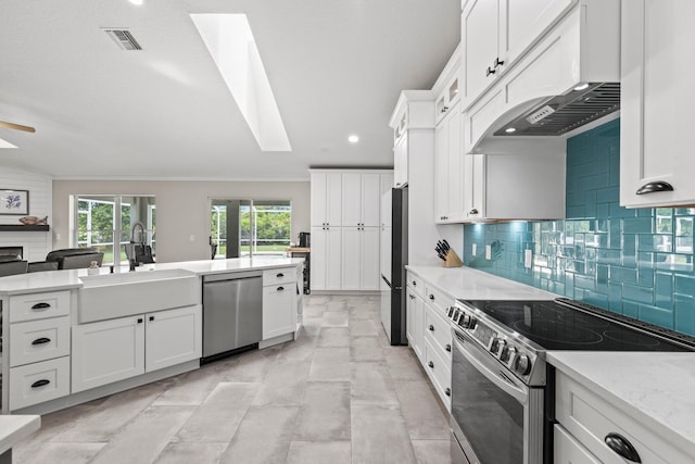 kitchen featuring white cabinets, stainless steel appliances, a skylight, and sink