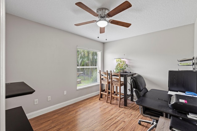 home office featuring ceiling fan, light hardwood / wood-style floors, and a textured ceiling